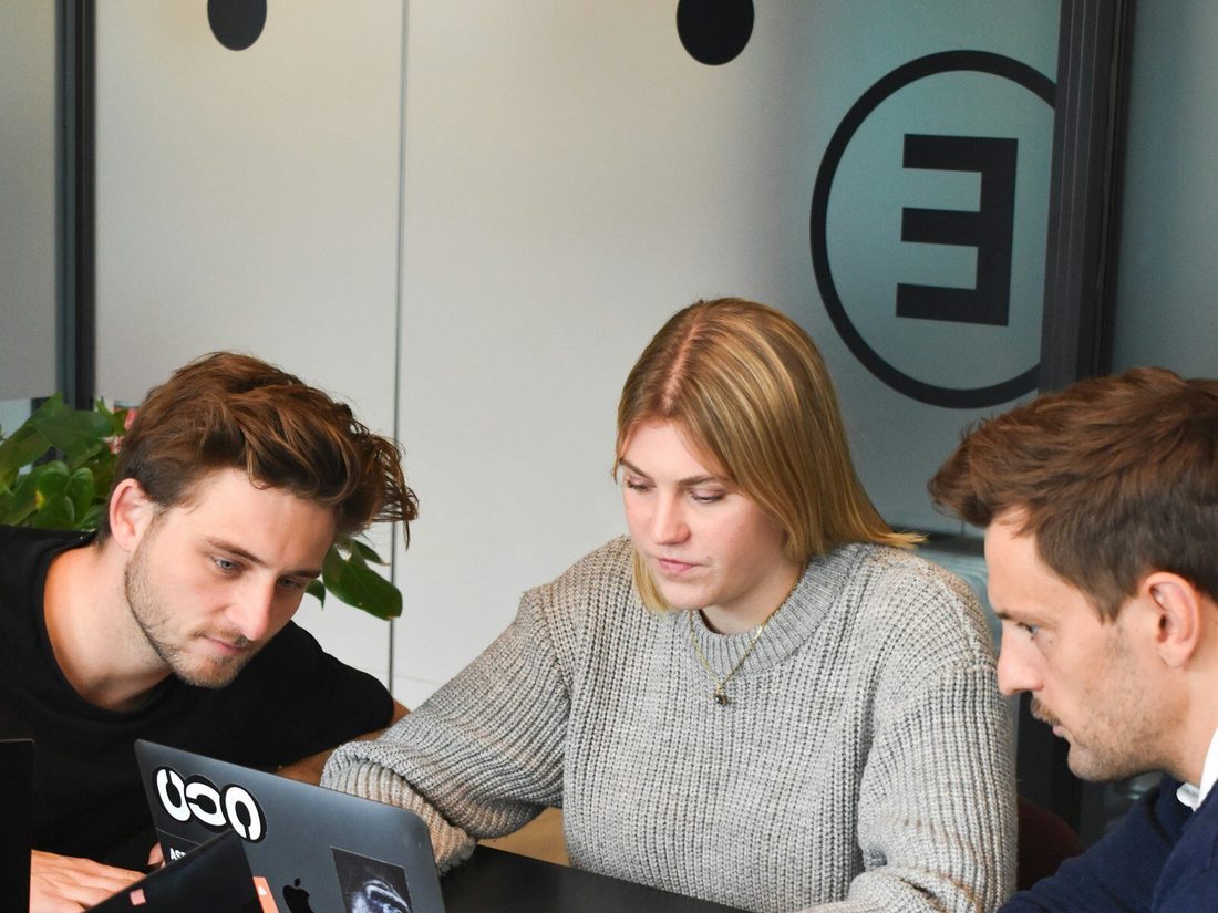 Drei Personen arbeiten gemeinsam an einem Notebook